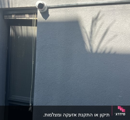 מצלמת אבטחה מותקנת על קיר חיצוני ליד חלון.
